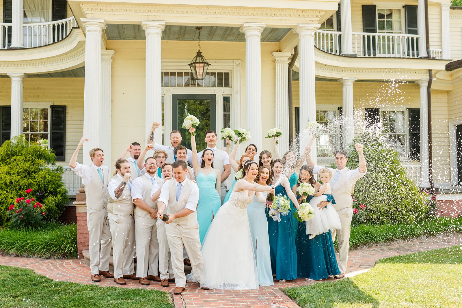 Champagne pop during Wedding Party Portraits with mix matched blue dresses at Summer Belle Grove Wedding by Richmond Wedding Photographer
